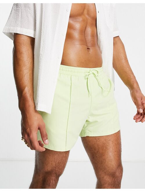 ASOS DESIGN swim shorts with curved hem in lime green short length