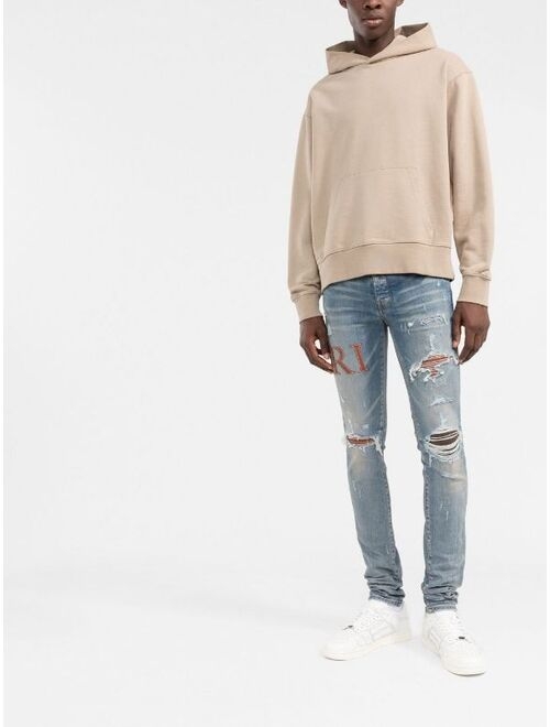 AMIRI logo-embellished distressed jeans