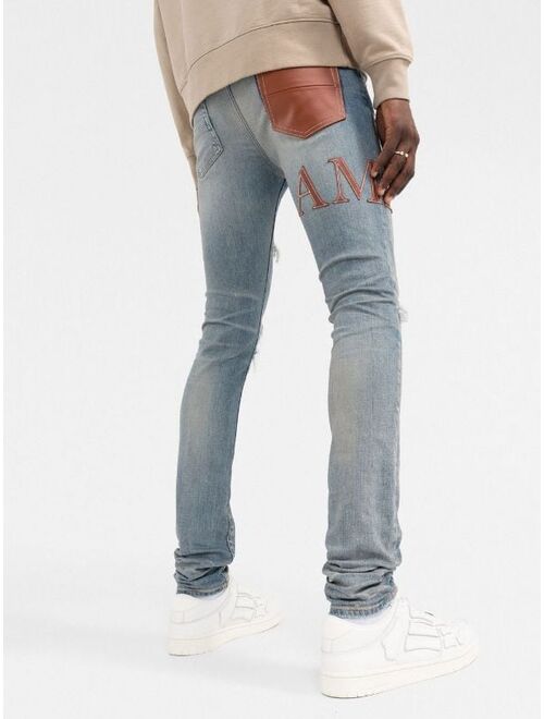 AMIRI logo-embellished distressed jeans