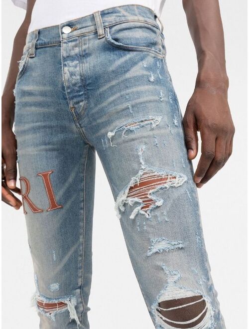 AMIRI logo-embellished distressed jeans