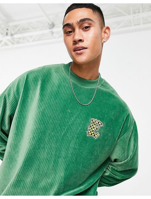 ASOS DESIGN oversized sweatshirt in green ribbed velour with varsity badge