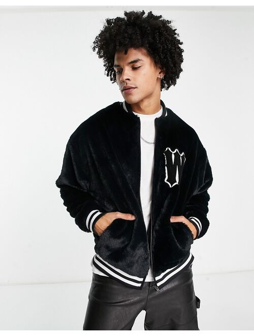 ASOS DESIGN oversized varsity faux fur jacket in black with badge and tipping