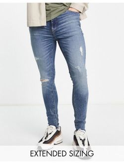 spray on jeans with power stretch in mid wash blue with tint and abrasions