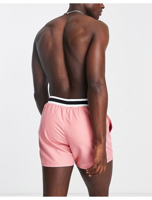 ASOS DESIGN swim shorts in short length with smart styling and contrast rib in pink